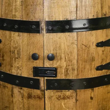 Bourbon Whiskey barrel cabinet with doors closed and safety hasp closed. Metal rings painted black to match hardware