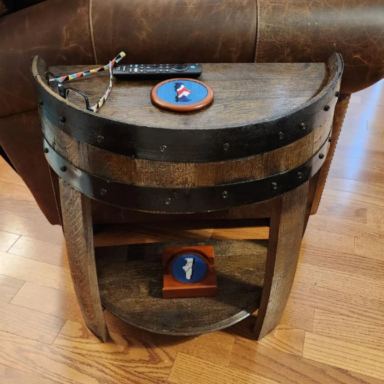 Half round whiskey barrel end table with a walnut stain. Metal rings are painted black to accent the barrel