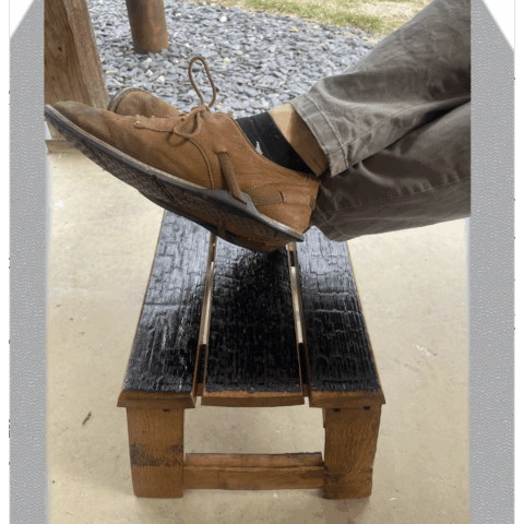 Barrel stave footrest with someone's feet resting on it
